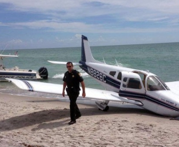 Equipes de emergência são vistas ao lado de avião que caiu em praia da Flórida neste domingo (27), matando um homem e ferindo sua filha de 9 anos. Ambos estavam na areia e foram atingidos pela aeronave 