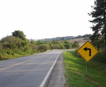 Placa, na PR-151 entre Palmeira e São João do Triunfo, indica curva acentuada à esquerda sendo que, adiante, a estrada segue para a direita 