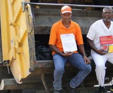 De blusa laranja, Milton Marinho exibe certificado de conclusão do Ensino Médio; de uniforme branco, Domingos Costa carrega livro de preparação para o Enem 