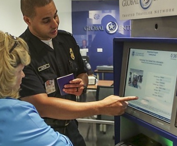 Funcionário da imigração americana explica uso da máquina do sistema Global Entry a usuária 