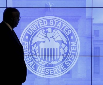 Segurança passa em frente a uma imagem do Fed após reunião do Fomc em Washington, nesta quarta (27)