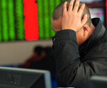 Investidor olha para painel de ações em Fuyang 