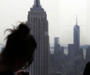 Mulher tira foto do Empire State Building (à esq.) ao lado do One World Trade Center (centro) 