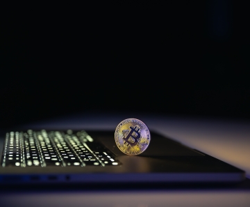 moeda_de_bitcoin_perto_de_laptop_em_fundo_preto_conceito_de_financas_e_dinheiro_criptografico